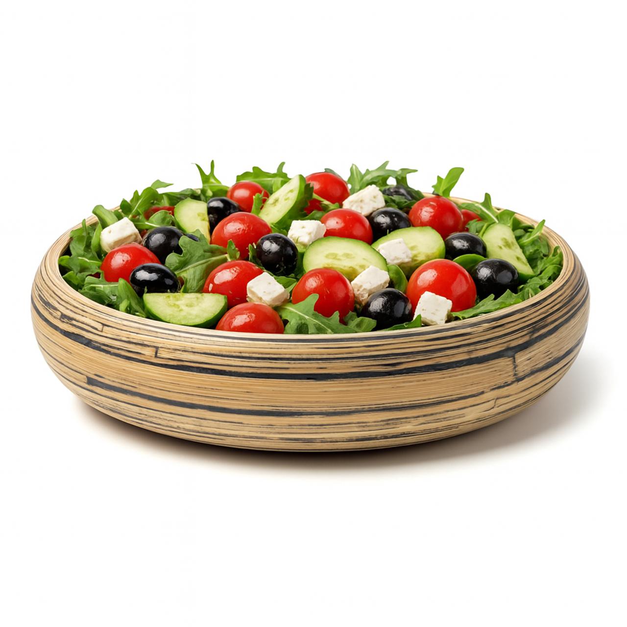 Natural bamboo serving bowl filled with fresh Greek-style salad: arugula greens, cherry tomatoes, cucumber slices, black olives, and feta cheese on white background